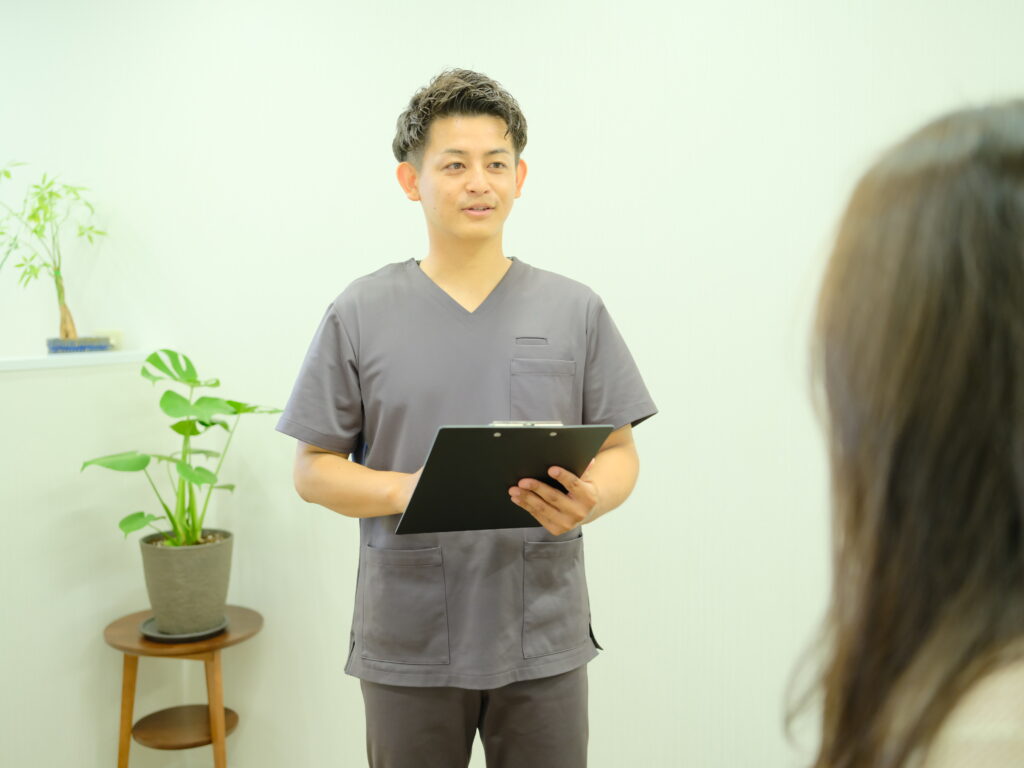 整骨院で施術内容の説明を受ける患者と施術者