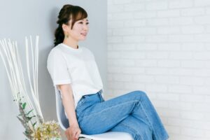 椅子に座って足を組むデニム姿の日本人女性