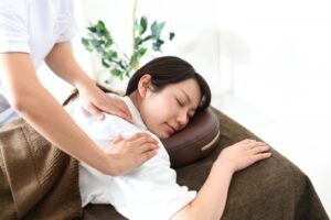 ベッドでマッサージ（整体）を受ける若い女性