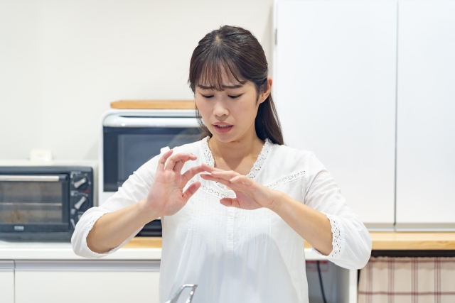 指が曲がらず痛みに悩む女性が手を見つめている様子