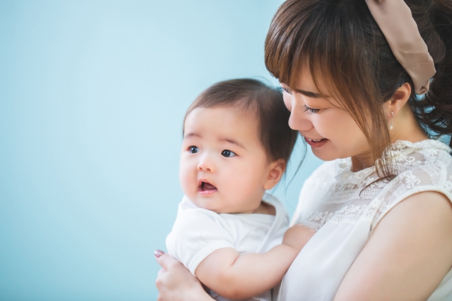 赤ちゃんを抱っこする笑顔の若いママ