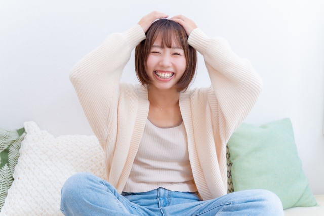 頭を両手で押さえて笑う女性