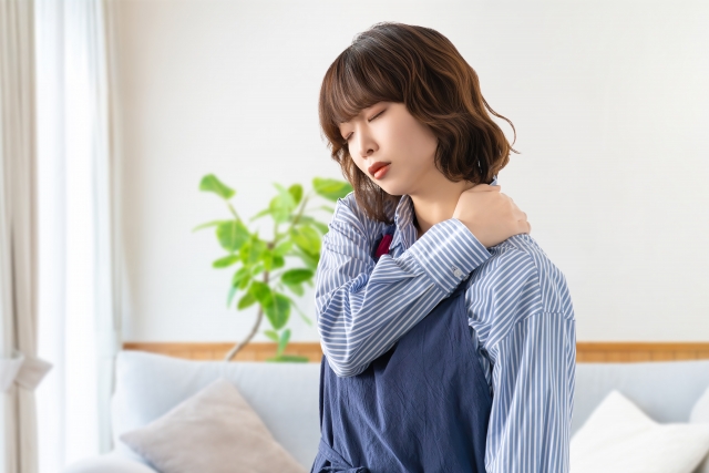 肩こりに悩むエプロン姿の女性