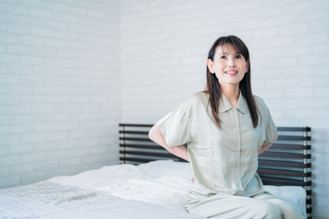 腰痛が改善し腰を押さえるミドル世代の女性