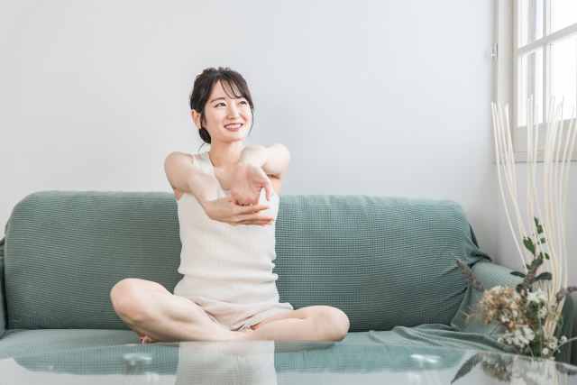 家のソファでストレッチする若い女性