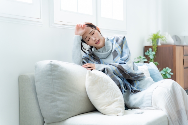 33789538_s 冷え性による頭痛でソファに座る女性