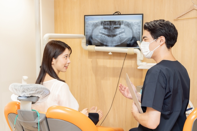 歯科医院でレントゲンをみながら説明する医師と患者