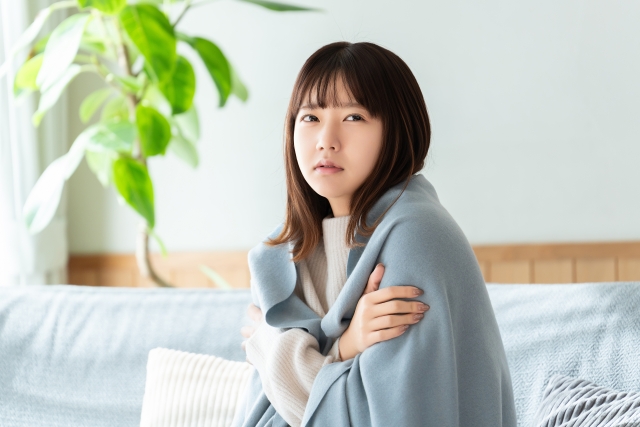 寒気がしてブランケットを羽織る女性