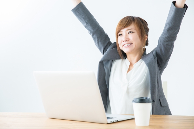 デスクで背伸びする女性