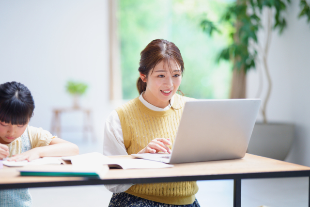 笑顔でパソコン作業をする母と勉強中の娘