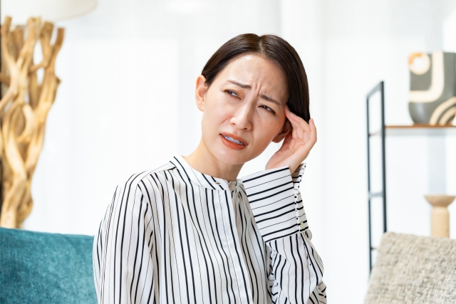 めまいで頭を抑える女性