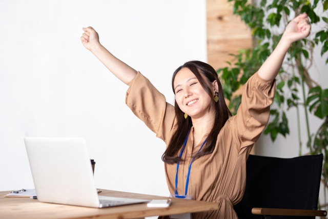 オフィスでバンザイ・リフレッシュ・深呼吸する女性