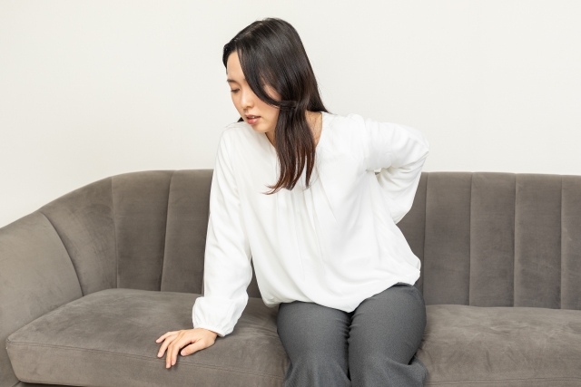 腰の痛みを感じる女性