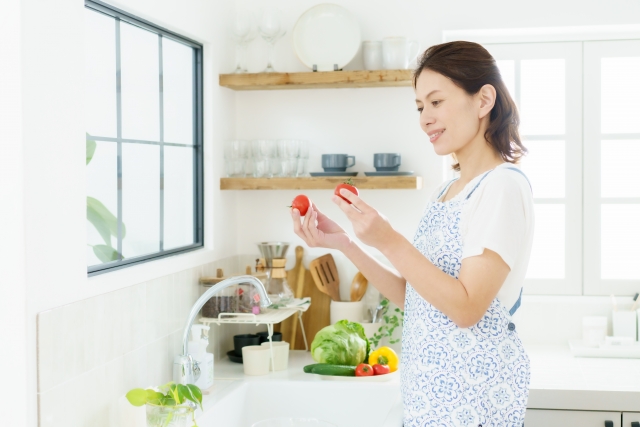 プチトマトを手に持つ笑顔の主婦