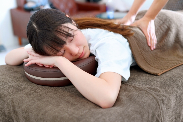 ベッドでマッサージ(整体)を受ける若い女性