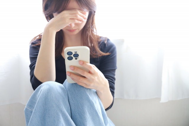 スマートフォンを見て落ち込む女性